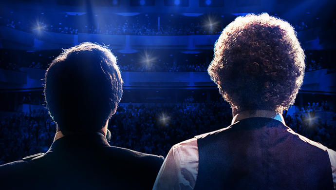 Two men stand in front of a stage, ready to perform as a tribute act to Simon & Garfunkel