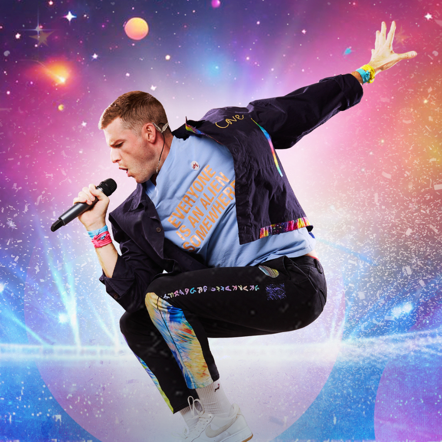 A man wearing a blue jacket jumps high into the air with microphone