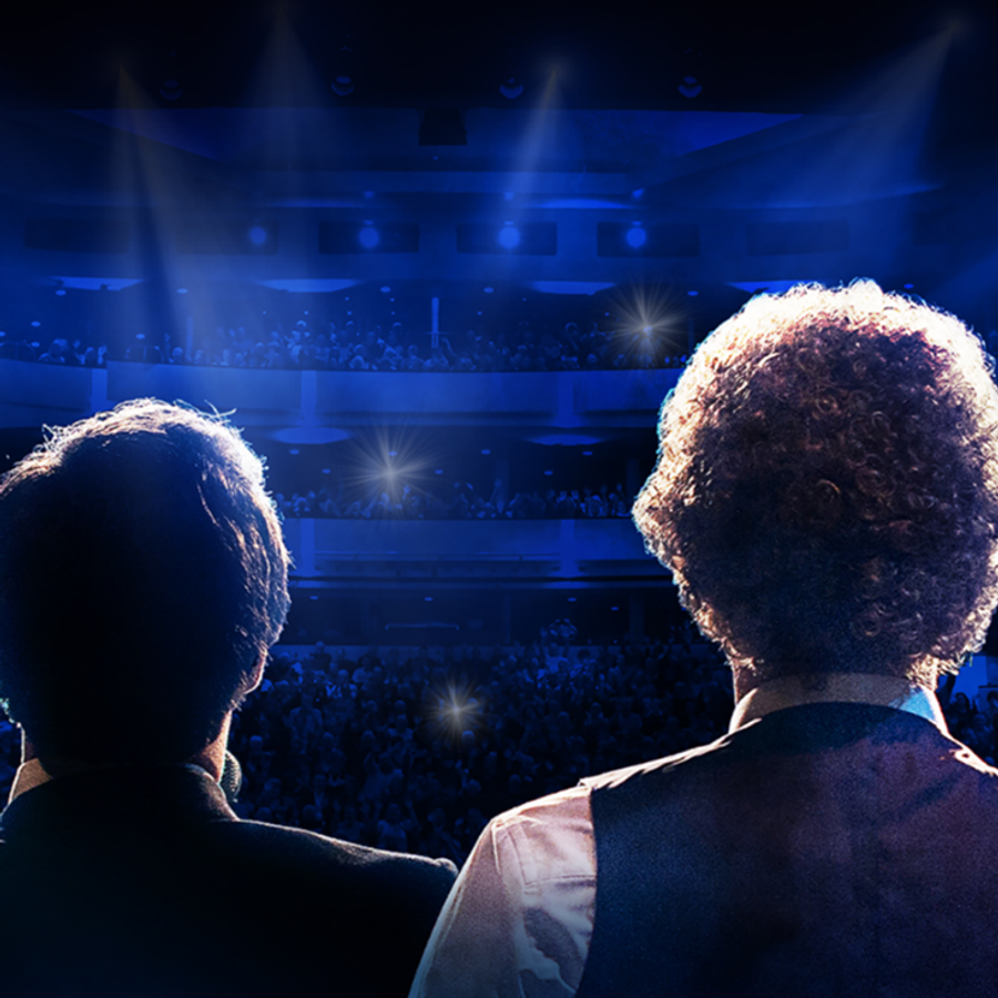 Two men stand in front of a stage, ready to perform as a tribute act to Simon & Garfunkel